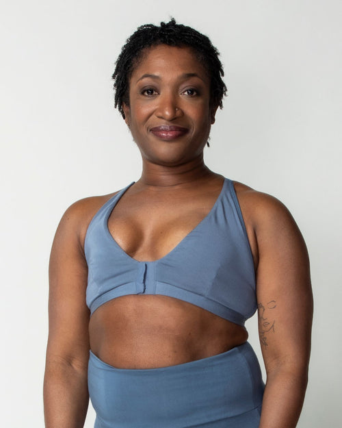 Slate / Implants & pocketed front closure lace racerback bra with a plunging neckline and soft wire free cups on implant reconstruction model.